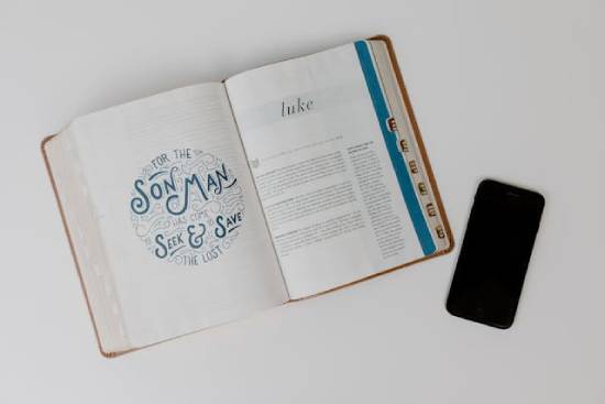 A phone with a Bible next to it that is open to the first page of Luke A phone with a Bible next to it that is open to the first page of Luke