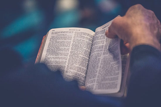 A person leafs through the pages of a Bible