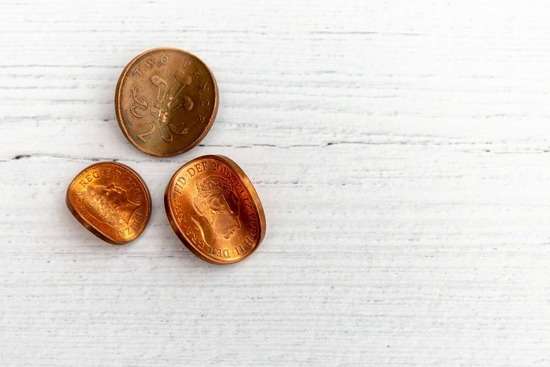 Three Copper Coins that are Slightly Bent Sitting on a Table Three slightly bent copper coins represent the negative view Pharisees and Sadducees had of tax collectors.