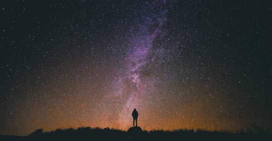 Milkyway A silhouette of a man standing under a vast, starry sky