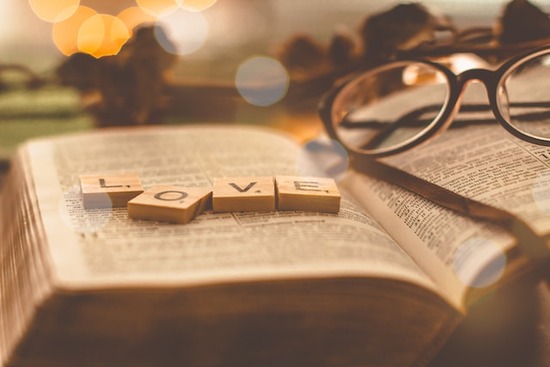 Word Love Open Bible Scrabble letters spelling L-O-V-E on top of an open Bible