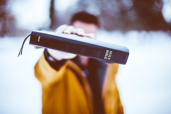 A man holding the Bible out to the viewer