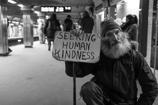 Man with Sign Seeking Kindness A homeless man holding a sign asking for kindness