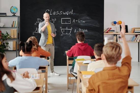 A teacher calling on a student who has his hand raised during math class.